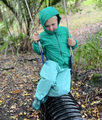 Child playing on a swing wearing spearmint children's overpants