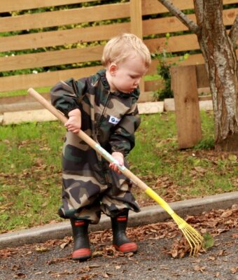 Child Raking Leaves wearing Mud MatesWaterproof Green Camo Children's Coveralls