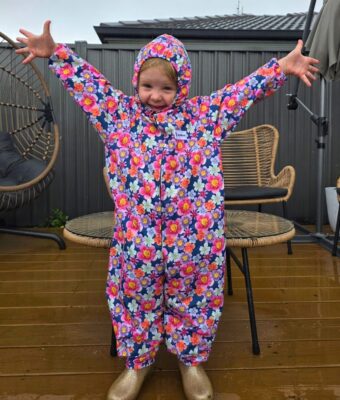 Girl smiling, wearing floral pattern children's coveralls