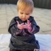 Toddler wearing a Mud Mates NZ-made navy blue craft apron/art smock with paint on her hands