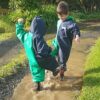 Children splashing in muddy puddles, keeping clean and dry in their Mud Mates waterproof childrens coveralls