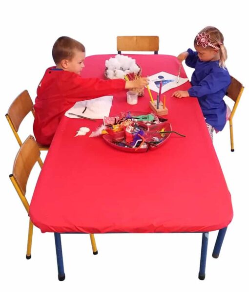 Red, rectangle NZ-made elasticated Fitted Tablecloth protecting a table during arts and crafts at an early childcare centre.