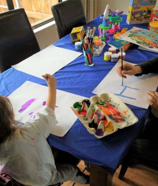 Kids painting at a dining room table protected with a Mud Mates elasticated fitted tablecloth