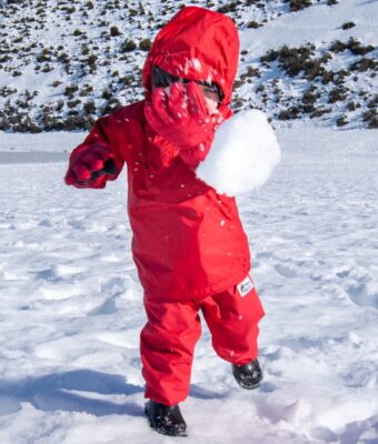 Child throwing a snow ball at the camera wearing Mud Mates NZ-made red Fleece Lined Pants