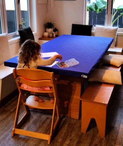Young child drawing at a dining room table protected with a Mud Mates elasticated fitted tablecloth