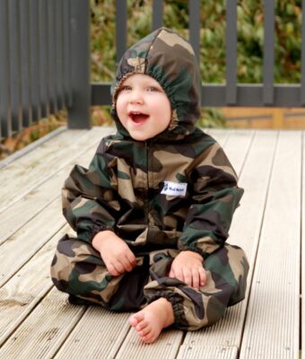 Young child sitting wearing Mud Mates NZ-made green camo waterproof coveralls