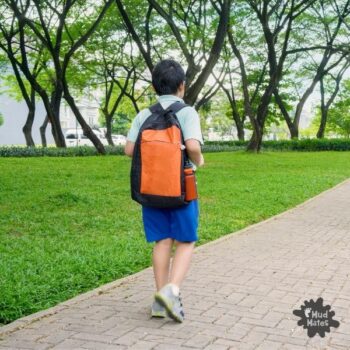 Young boy walking back to school with school bag on his back