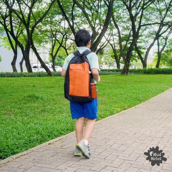 Young boy walking back to school with school bag on his back