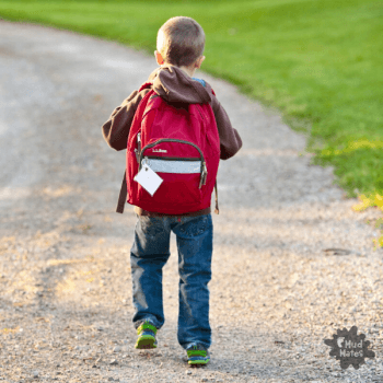 Young boy walking back to school with school bag on his back