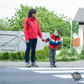 Mum holding child's hand at pedestrian crossing to teach road safety skills