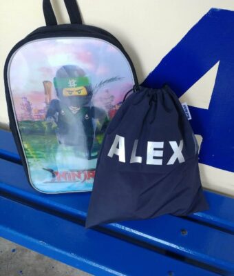 Navy Kids Waterproof Swim Bag / / Wet Bag sitting on bench with a school bag ready for swimming lessons