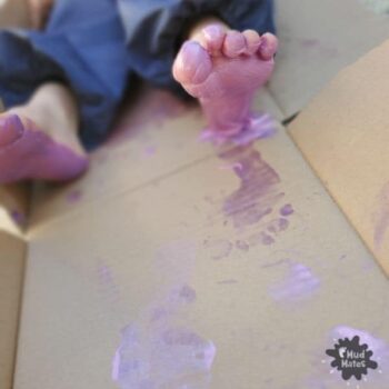 Sensory Feet Play Ideas - toddler with paint on her feet and footprints on cardboard