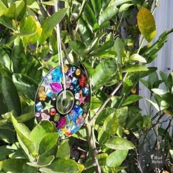 Spring Art Ideas: a jewelled CD wind spinner hanging from a leafy bush
