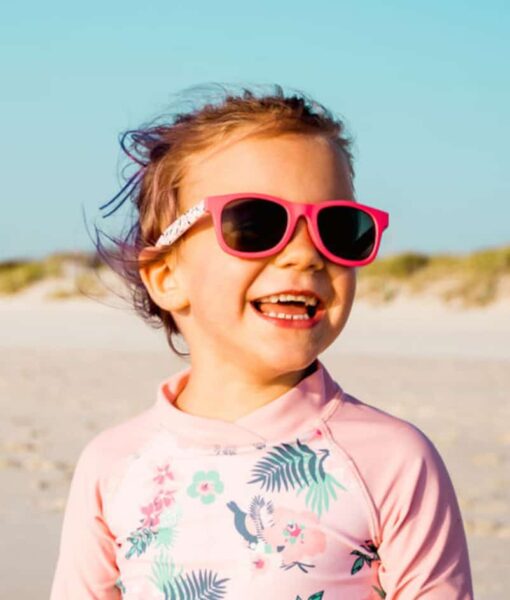 Young girl on the beach wearing Beachcomber Cherry Floral kids sunglasses