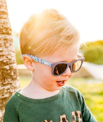 Toddler standing outside in the sun wearing Beachcomber Starry Nights kids sunglasses