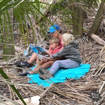 Mum and 2 young children reading outdoors in the bush
