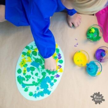 Child creating a pom pom easter egg art wearing a Mud Mates NZ-made apron