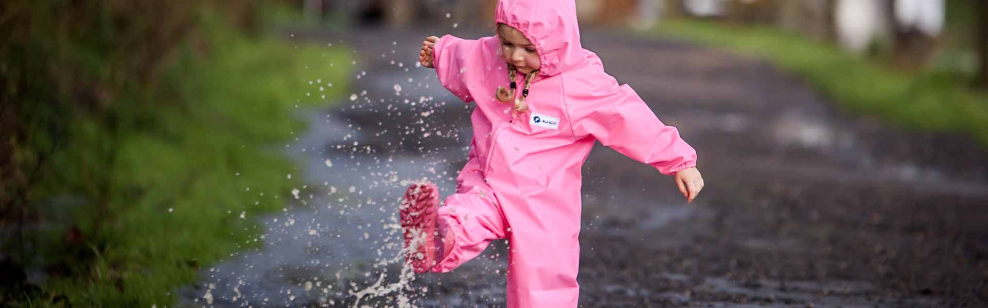 Young child splashing in water wearing Mud Mates NZ-made waterproof overalls