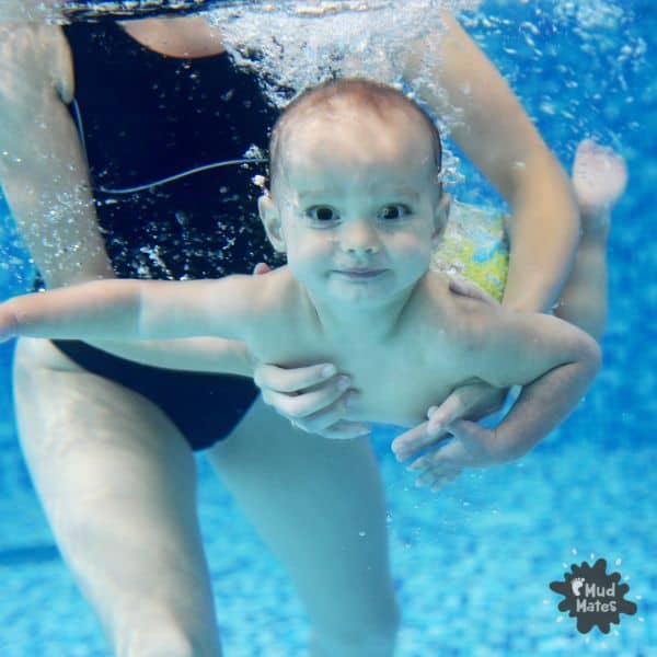 6 Benefits of Baby Swimming Lessons. Baby swimming under water being held by mum.