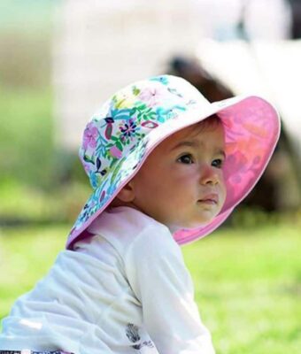 Baby girl wearing a Botanical design reversible sun hat. Shop UPF 50+ reversible kids sun hats