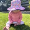 Baby wearing a Reversible kids sun hats - Rainbow pattern with solid purple on the reverse. UPF 50+ fabric for sun protection