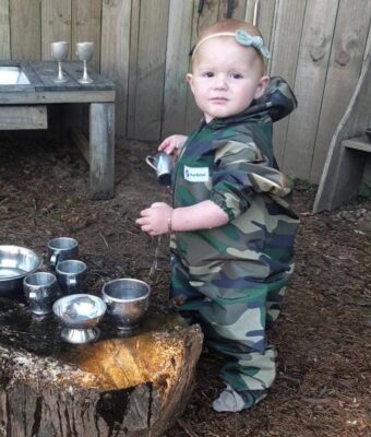 Toddler enjoying water play, keeping clean and dry in her Mud Mates waterproof Coveralls and Shoe Covers. Save money with a Little Explorer Value Pack