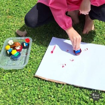 Young child ice painting on paper, using frozen ice paints