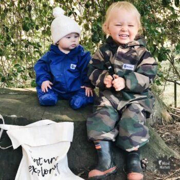 2 kids wearing Mud Mates waterproof coveralls enjoying outdoor play with a nature hunt