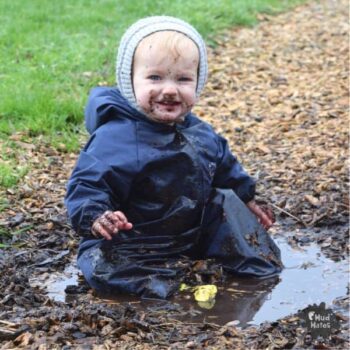 Young child sitting in a muddy puddle - Your Guide to International Mud Day Fun