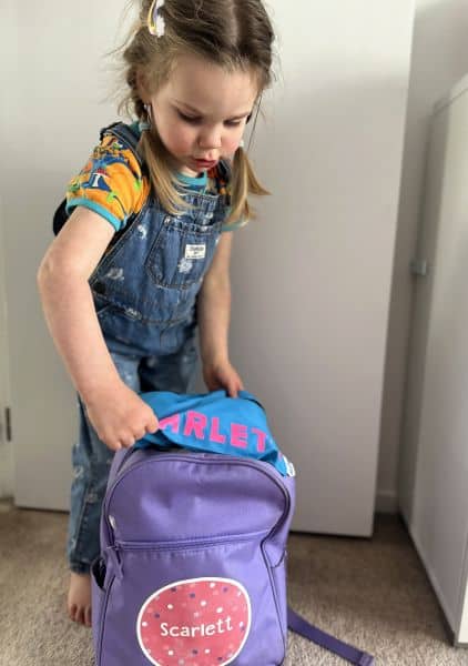 Young child packing her school bag: back to school organisation for kids