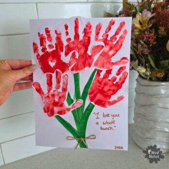 A Valentine’s Day handprint craft made with children’s painted handprints turned into flower shapes on card.