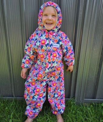 Girl smiling, wearing floral pattern children's coveralls
