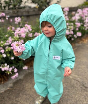 Young child keeping clean and dry in her spearmint children's coveralls
