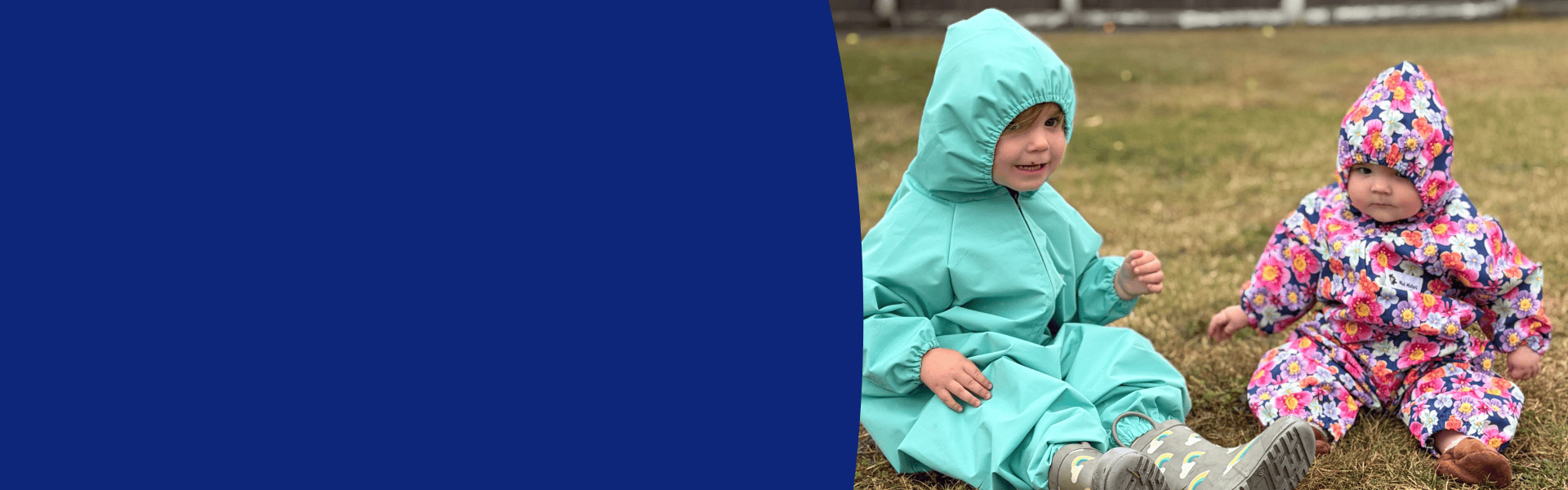 Two young children wearing Mud Mates mint and floral NZ-made waterproof coveralls playing outside