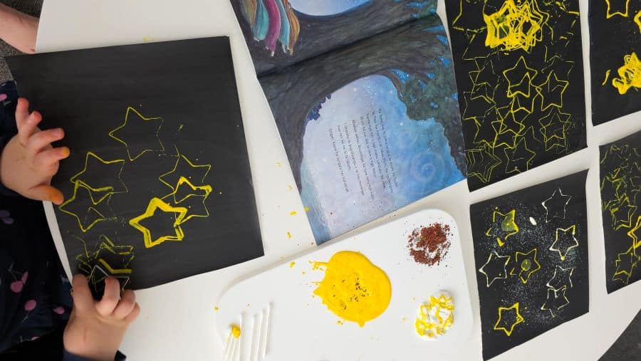 Matariki star stamping craft step by step - child hand-stamping stars onto dark card with a cookie cutter