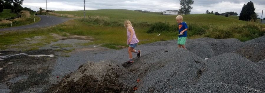 Kids playing outdoor play routine puddle jumping on gravel path