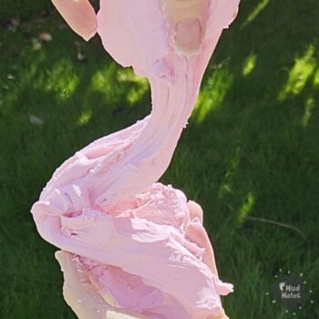 Homemade cloud dough being stretched between two hands - soft pink sensory play dough made from conditioner and cornflour