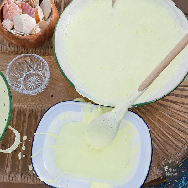 Whipped oobleck sensory play for kids - oobleck pouring slowly between trays outdoors